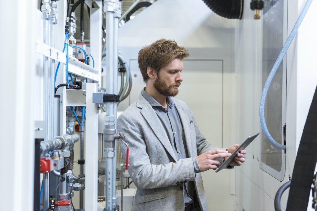 Businessman using tablet at machine in modern factory